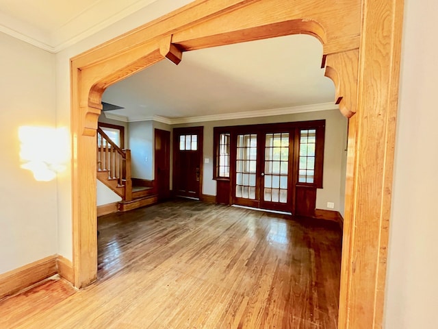 foyer with wood finished floors, stairway, baseboards, crown molding, and french doors