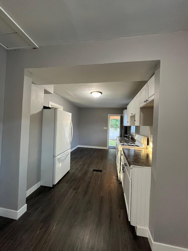 kitchen with white appliances, baseboards, dark wood-style flooring, and white cabinetry
