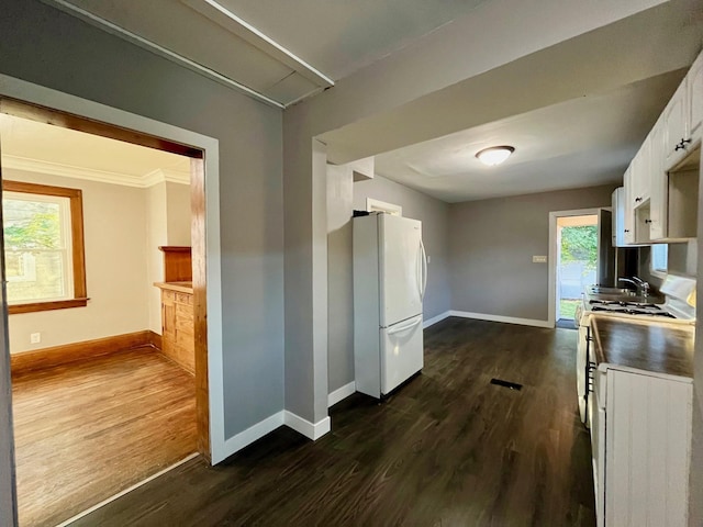kitchen featuring freestanding refrigerator, dark wood-type flooring, baseboards, and crown molding