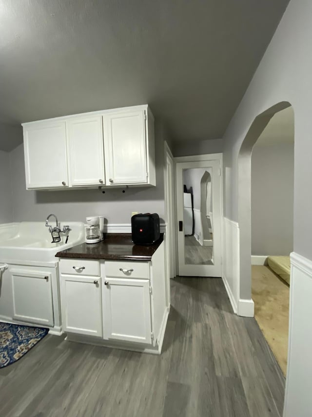bar featuring a sink, dark wood finished floors, and arched walkways