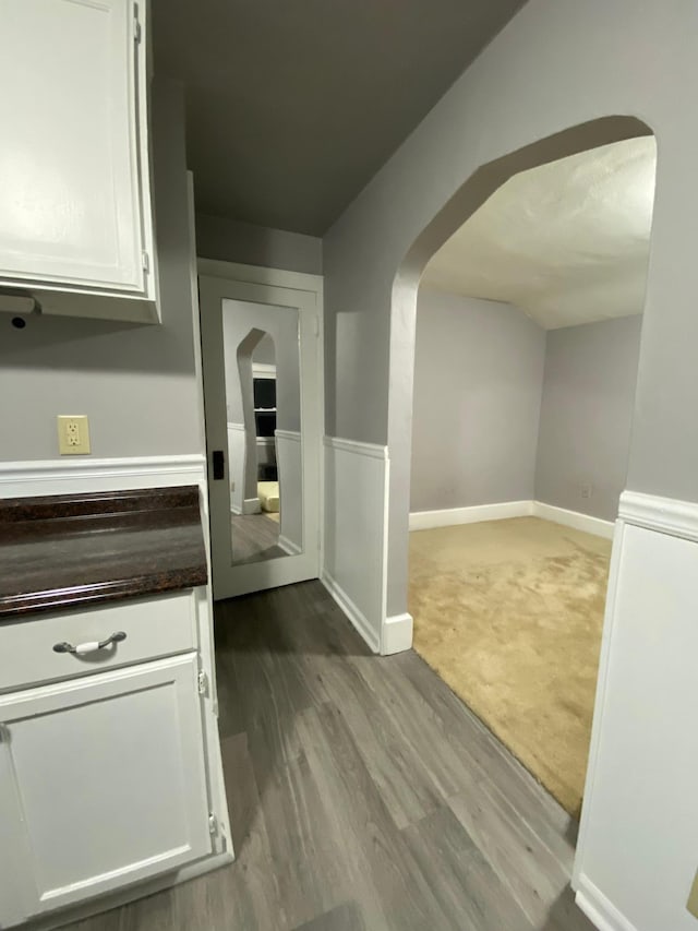hallway with arched walkways and wood finished floors