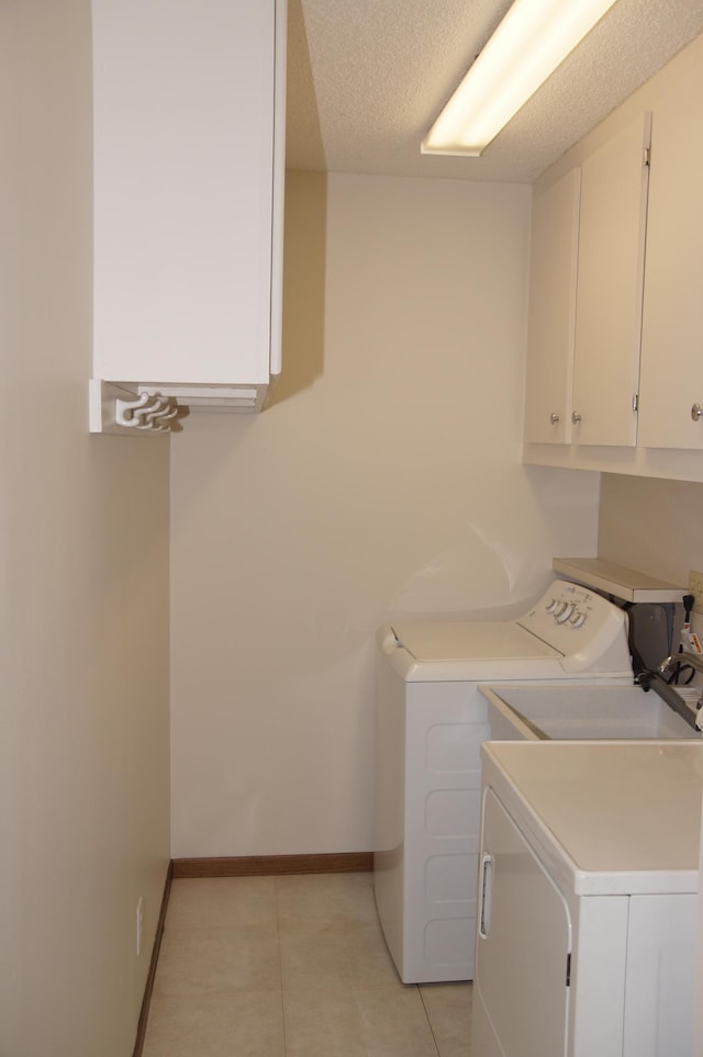 2140 Tamarin Trl, Golden Valley, MN 55427 - laundry area featuring washer and clothes dryer, cabinet space, light tile patterned flooring, baseboards, and a textured ceiling
