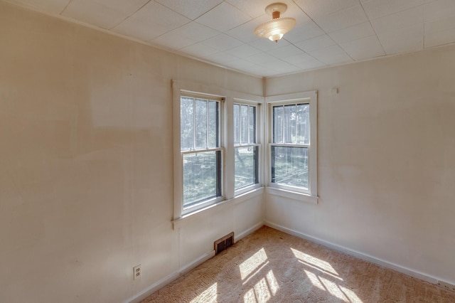 carpeted spare room featuring plenty of natural light and baseboards