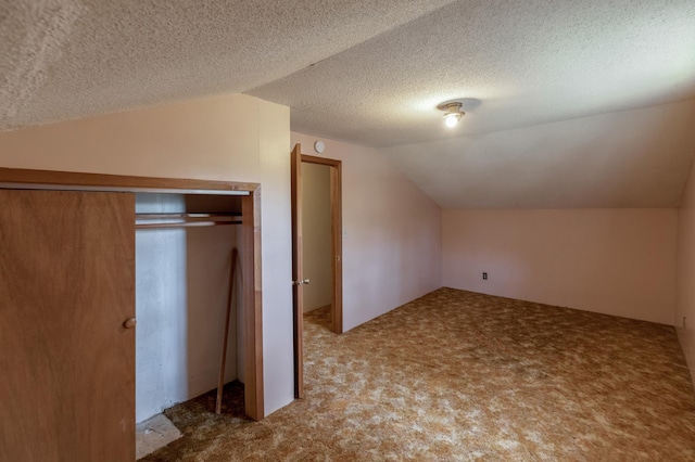 additional living space featuring vaulted ceiling, carpet floors, and a textured ceiling