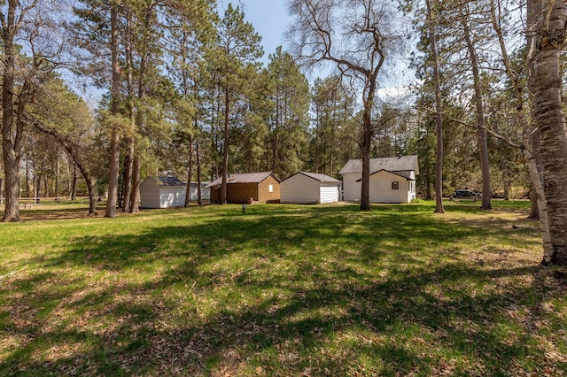 view of grassy yard featuring a storage unit and an outbuilding