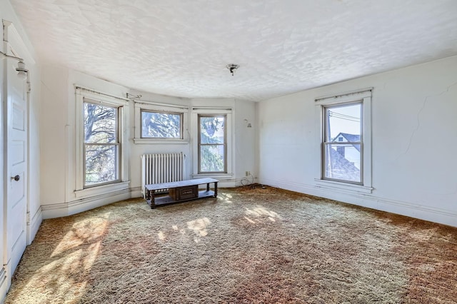spare room with radiator heating unit, healthy amount of natural light, a textured ceiling, and baseboards