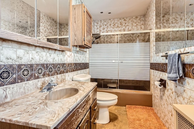bathroom featuring toilet, backsplash, combined bath / shower with glass door, and vanity