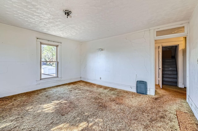 carpeted spare room with a textured ceiling and baseboards