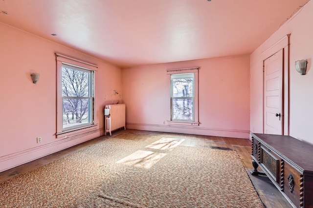bonus room with radiator heating unit, wood finished floors, and baseboards