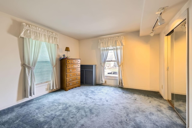 unfurnished bedroom with track lighting, carpet, and baseboards