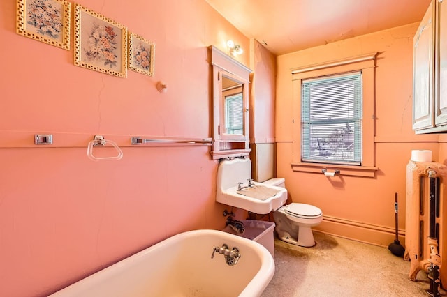 bathroom featuring a freestanding bath, toilet, a sink, and radiator