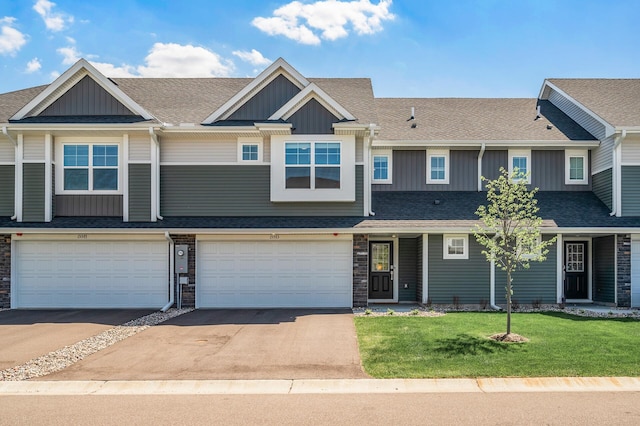 townhome / multi-family property featuring board and batten siding, driveway, a front yard, and stone siding