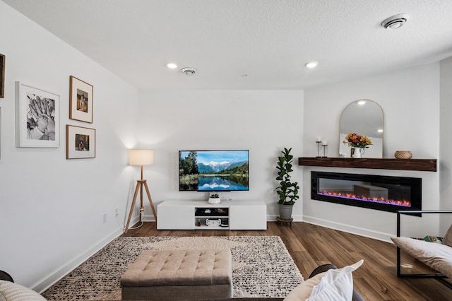 living room with baseboards, wood finished floors, recessed lighting, and a glass covered fireplace