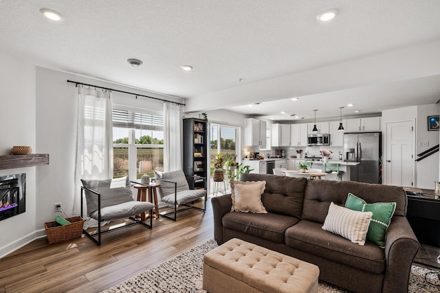 living room with light wood-type flooring, recessed lighting, baseboards, and a glass covered fireplace