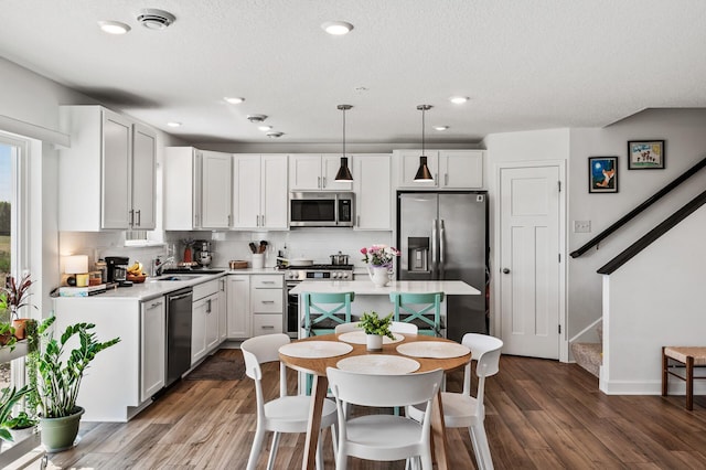 kitchen featuring appliances with stainless steel finishes, decorative backsplash, wood finished floors, light countertops, and recessed lighting