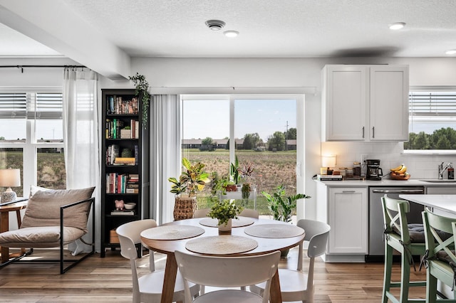 dining space with light wood-style flooring and a textured ceiling