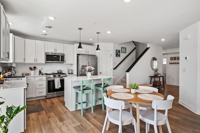 kitchen with stainless steel appliances, a sink, a kitchen island, tasteful backsplash, and light countertops