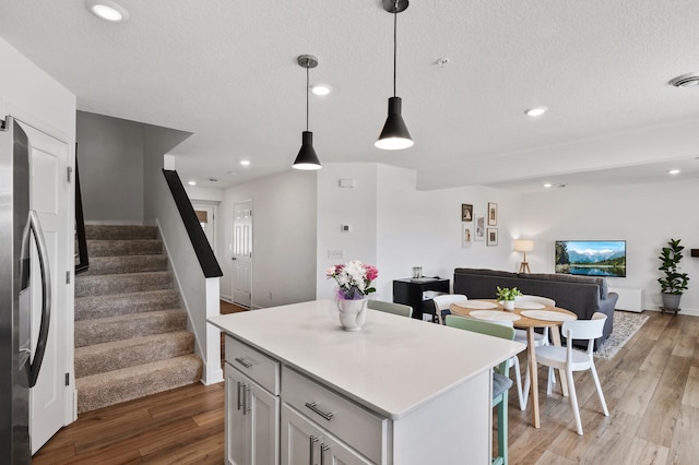 kitchen with light wood-style flooring, open floor plan, light countertops, freestanding refrigerator, and a center island