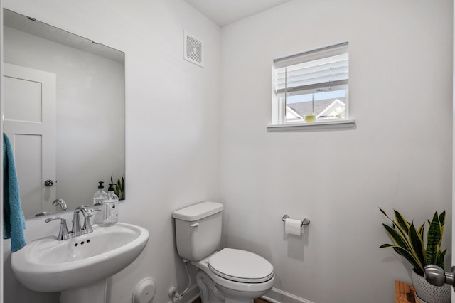 bathroom with a sink, toilet, and baseboards
