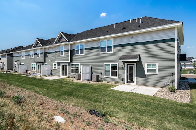 rear view of house featuring central air condition unit, a patio area, a lawn, and a residential view