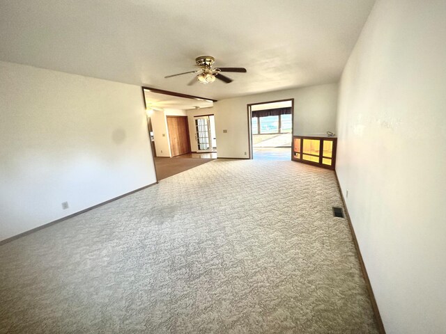 carpeted spare room with a ceiling fan and baseboards