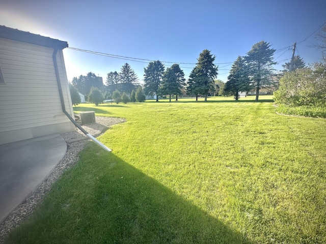 view of grassy yard featuring central air condition unit