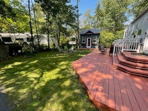 view of green lawn with a deck and an outbuilding