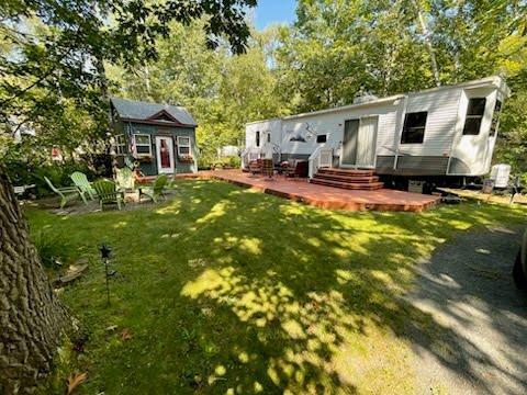 F6LOT139 Pathfinder Vlg, Clover Twp, MN 55037 - view of grassy yard featuring an outdoor structure, a deck, and view of wooded area