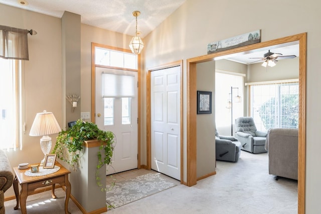 carpeted foyer entrance with ceiling fan and baseboards