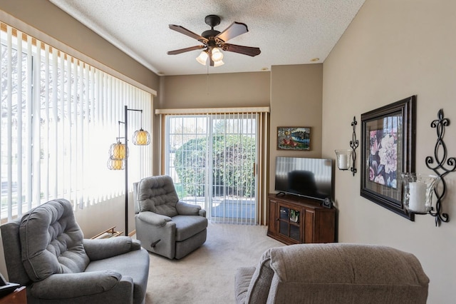 carpeted living area featuring ceiling fan and a textured ceiling