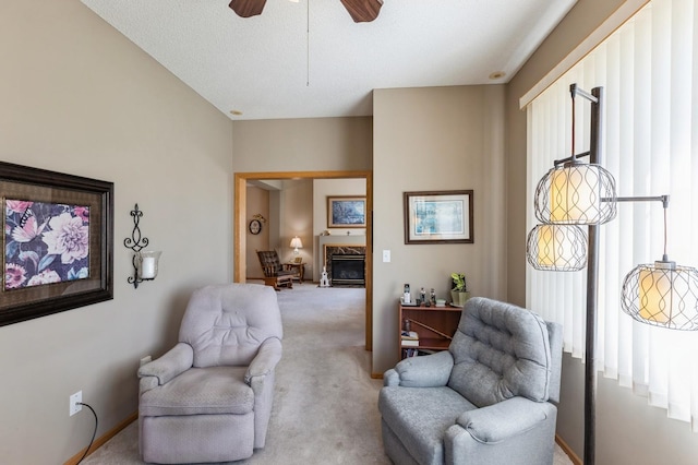 living area with carpet, a ceiling fan, a fireplace, and baseboards