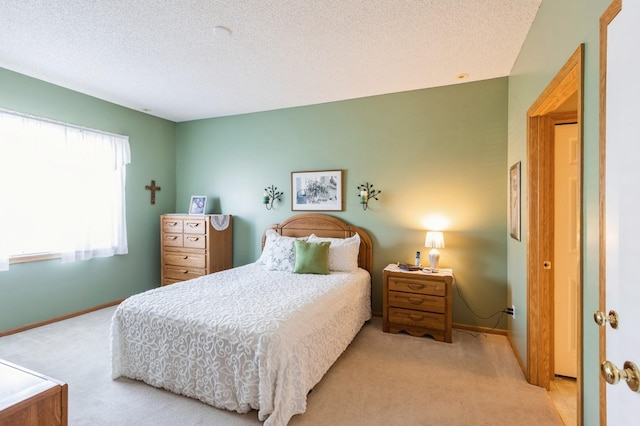 bedroom with light colored carpet, baseboards, and a textured ceiling
