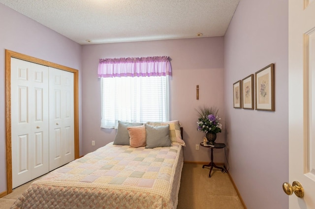 bedroom featuring light colored carpet, a closet, a textured ceiling, and baseboards