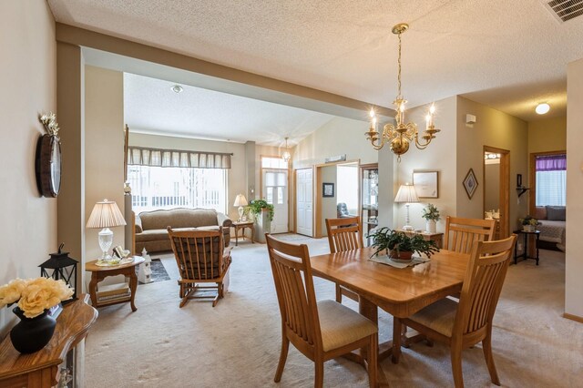 dining area featuring light colored carpet, a chandelier, and a textured ceiling