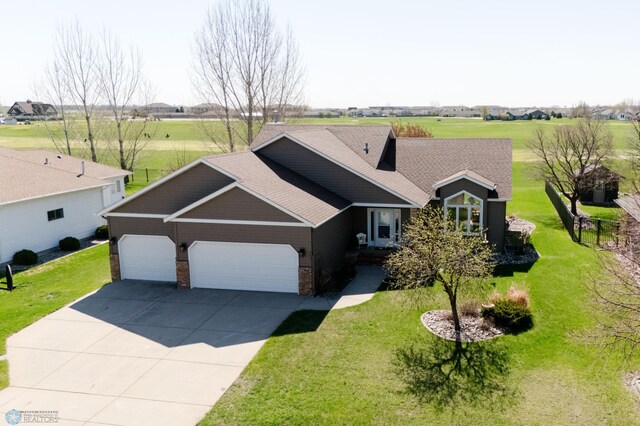 view of front of house featuring an attached garage, concrete driveway, and a front yard