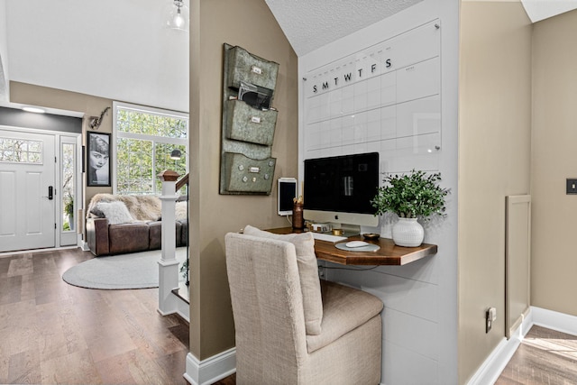 living area with vaulted ceiling, wood finished floors, and baseboards