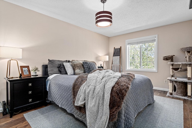 bedroom with dark wood-style floors, a textured ceiling, and baseboards