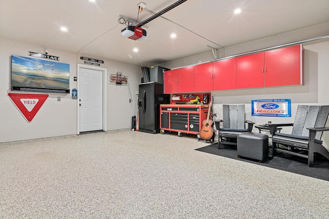 garage featuring a garage door opener, recessed lighting, and black fridge