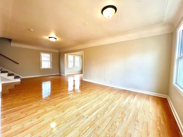 spare room with light wood-type flooring, stairway, and baseboards