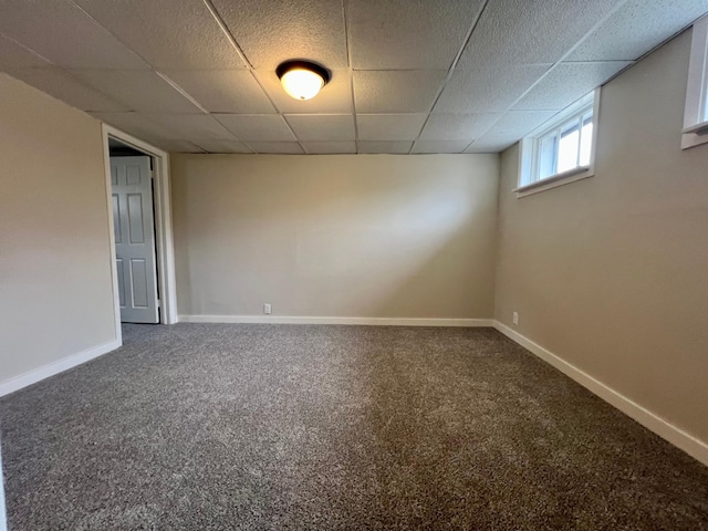 below grade area featuring a paneled ceiling, carpet floors, and baseboards