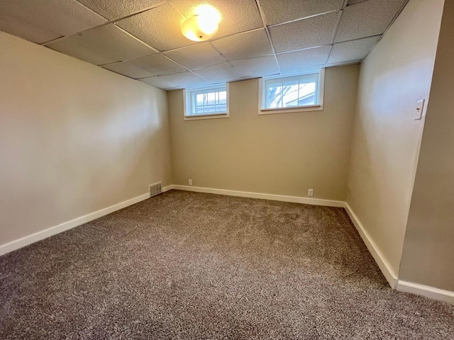 basement featuring carpet flooring, a paneled ceiling, and baseboards