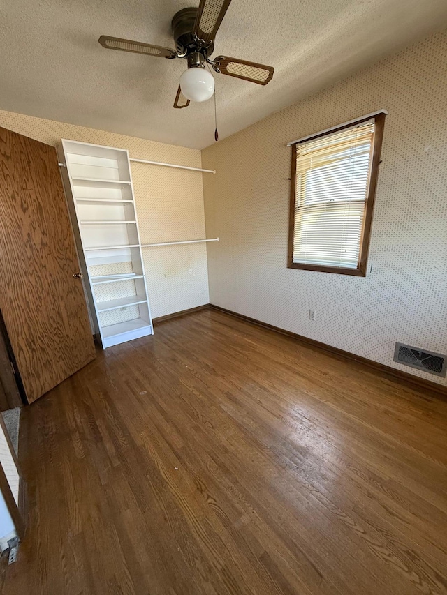 unfurnished bedroom featuring wood finished floors, baseboards, a textured ceiling, and ceiling fan