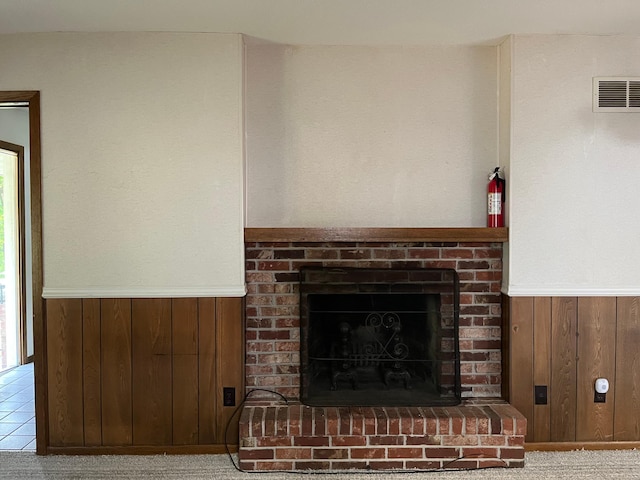 detailed view of wainscoting, a fire extinguisher, a brick fireplace, and wood walls