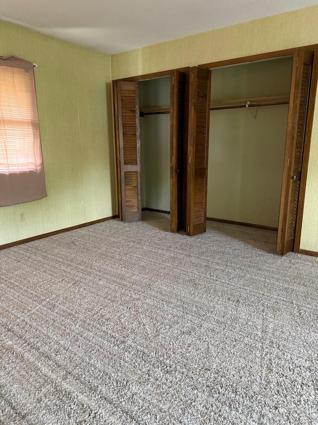 unfurnished bedroom with carpet, wallpapered walls, and baseboards