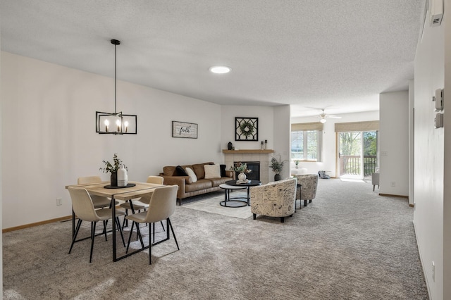carpeted living area featuring a textured ceiling, a fireplace, a chandelier, and baseboards