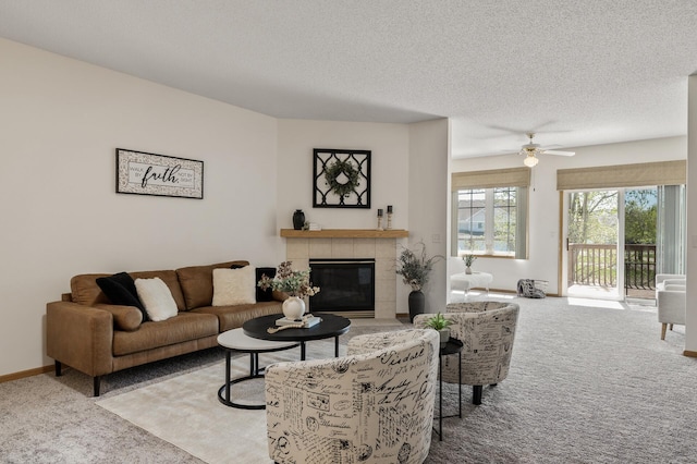 living area with carpet, a tiled fireplace, a textured ceiling, ceiling fan, and baseboards