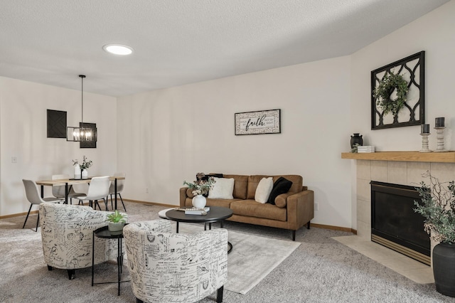 carpeted living room with a chandelier, baseboards, and a tile fireplace