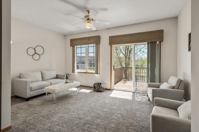 carpeted living area with ceiling fan, baseboards, and a textured ceiling