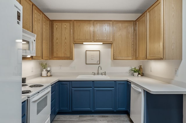 kitchen featuring white appliances, a sink, light wood-type flooring, and light countertops
