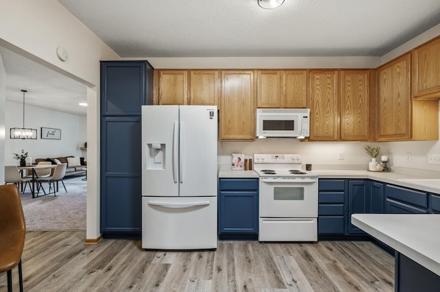 kitchen featuring white appliances, light wood-style floors, light countertops, a chandelier, and a sink